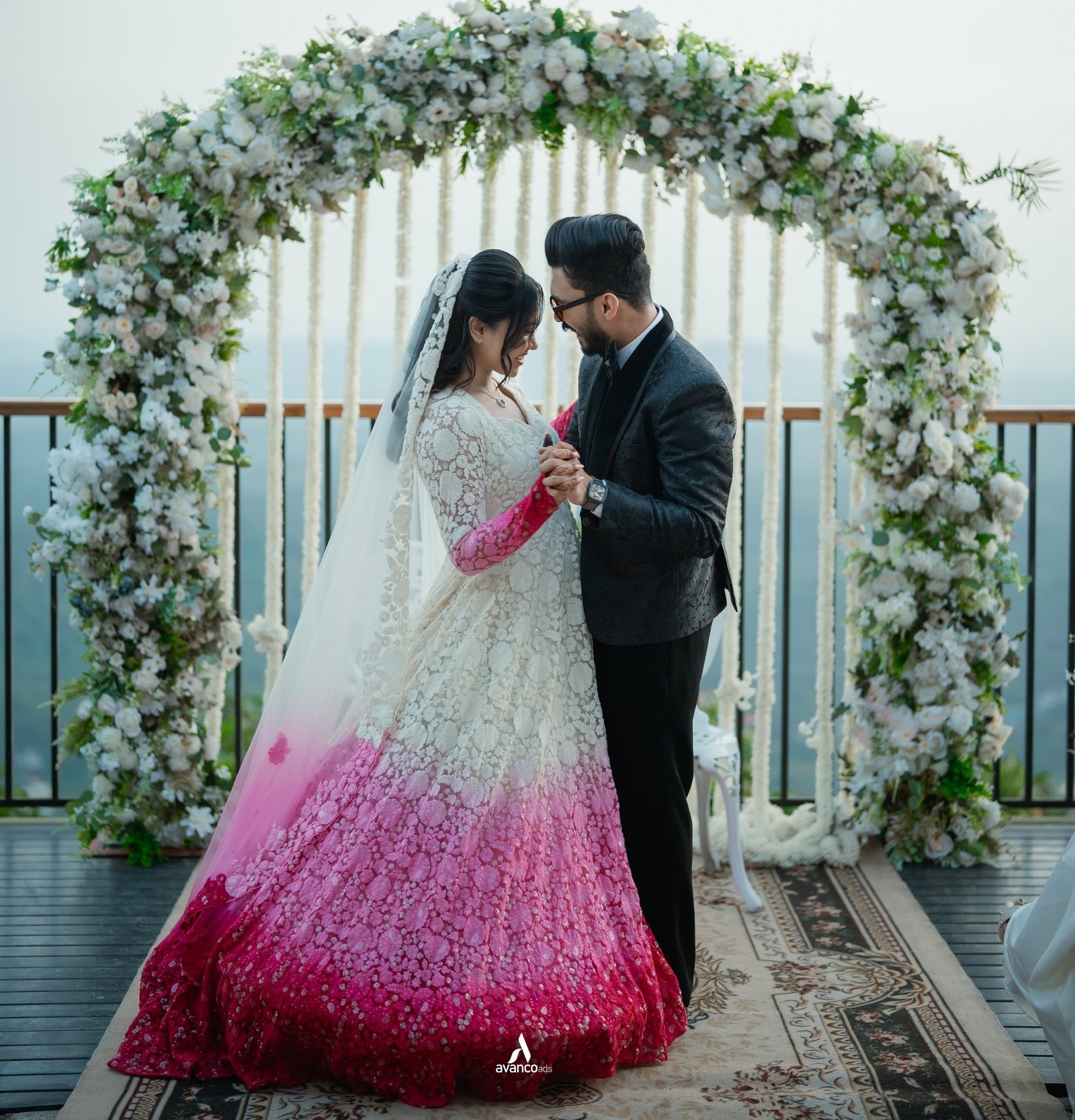 A bride and groom sharing a quiet moment beneath a floral arch
