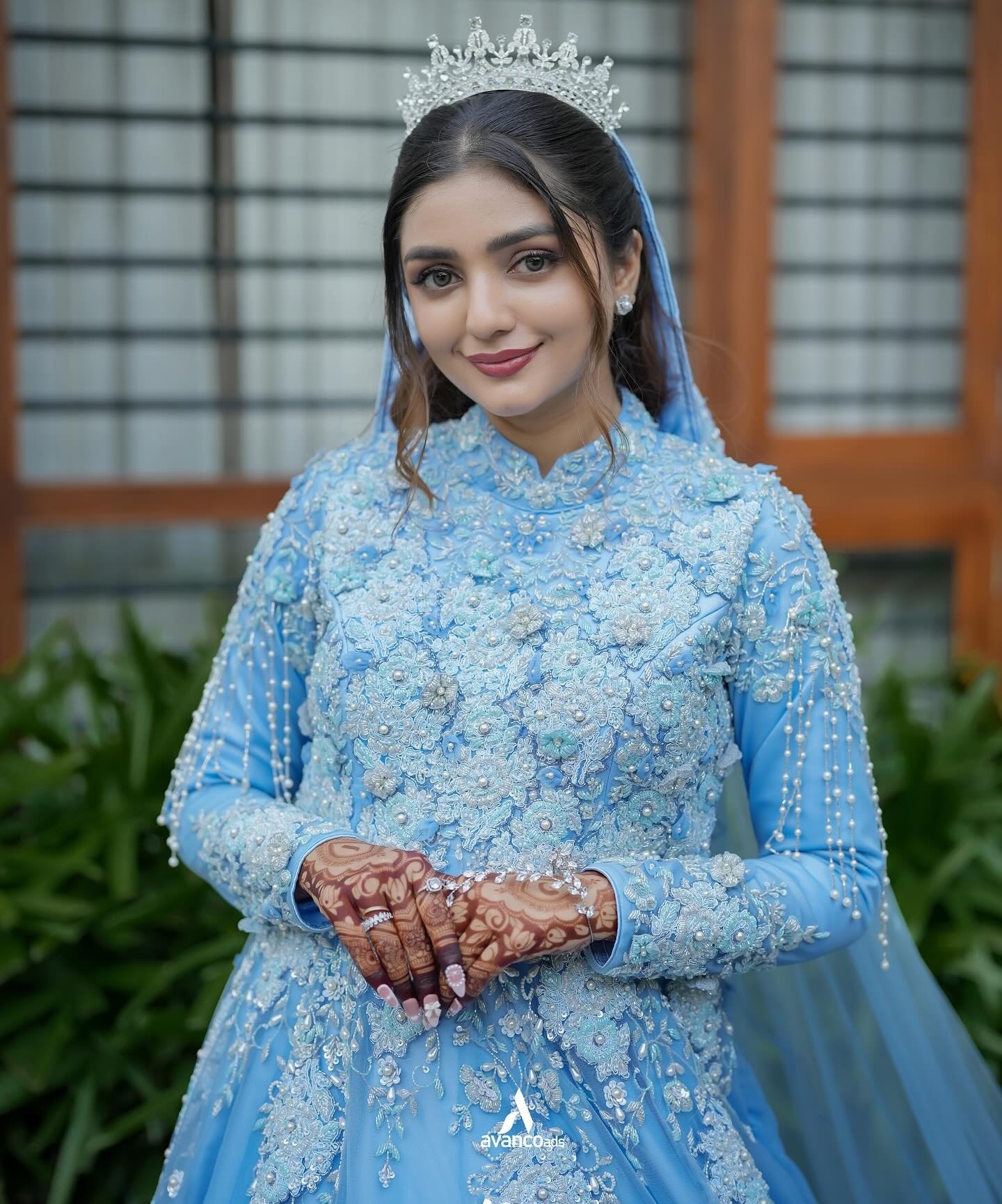 A bride in blue wedding attire with henna on her hands