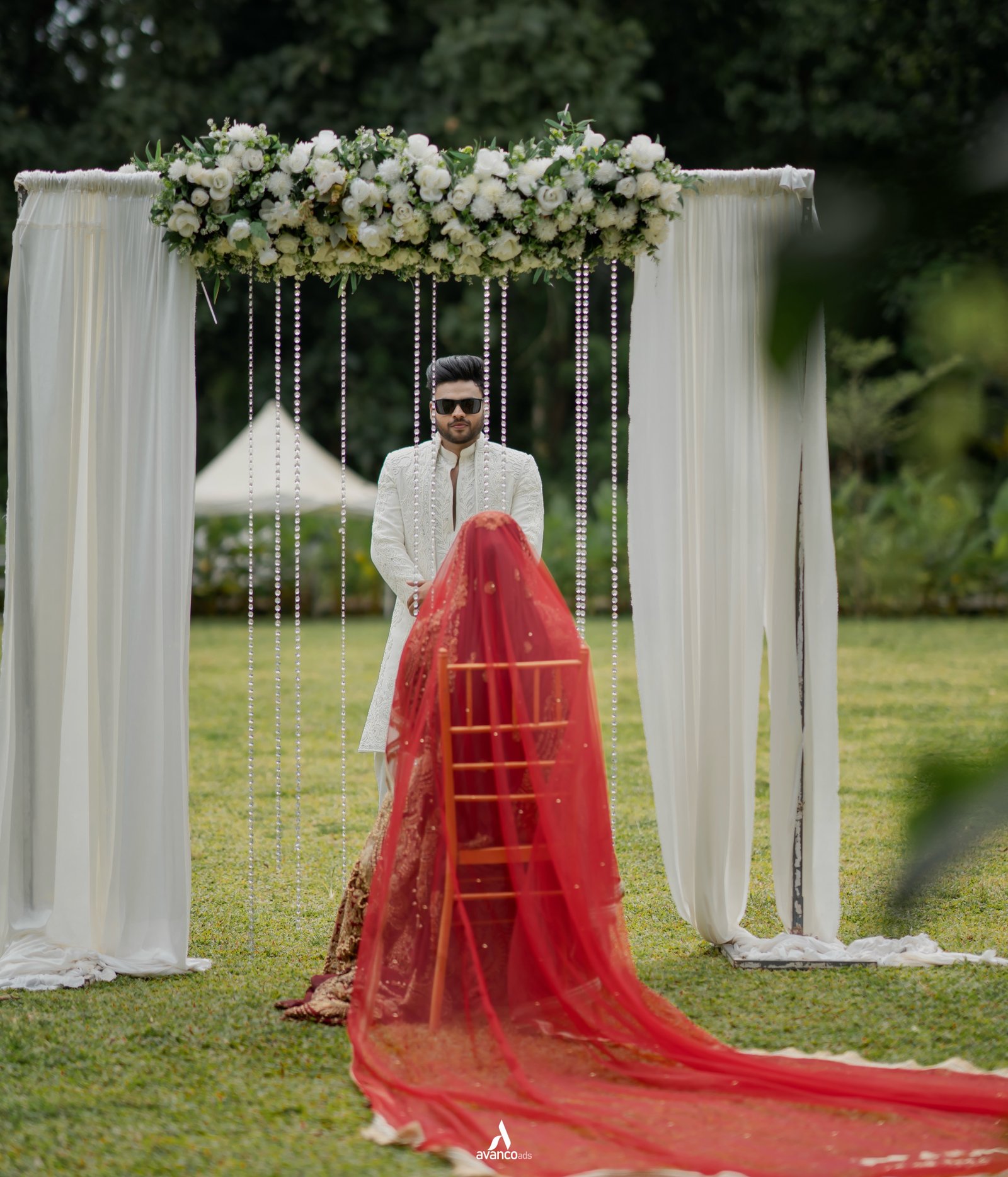 A groom waiting beneath a floral wedding canopy